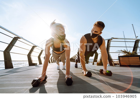 Young man and woman in protective masks running and doing exercises outdoors in the morning. Sport, Active. 103946905