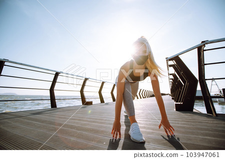 Young woman in protective mask. Sport woman doing stretching exercise near the sea. Sport, Active life. 103947061