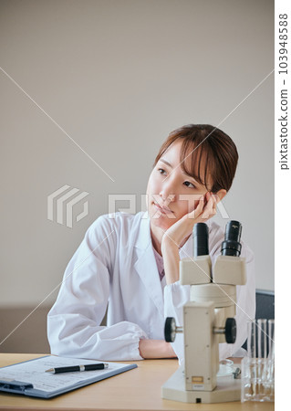 A young woman in a white coat thinking with her chin in her hands 103948588