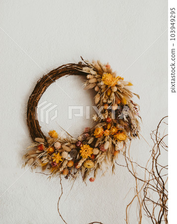 Natural beautiful wreath of various dried flowers and plants hang on the white wall background Natural beautiful wreath of various dried flowers and plants hang on the white wall background 103949295