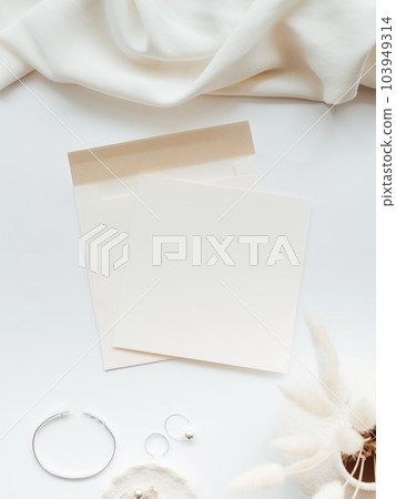 White blank paper sheet card mockup, envelope and floral branch in vase and silver jewelry on white background. 103949314