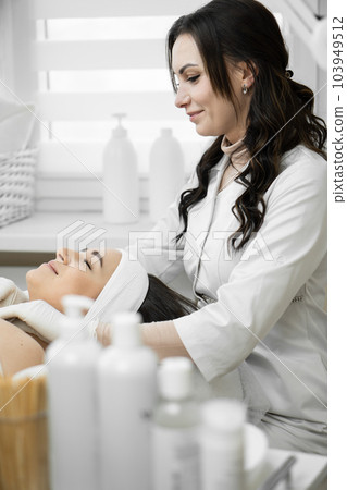 The magic of beauty shows how a cosmetologist in a beauty clinic performs a facial cleansing procedure, giving a woman an unsurpassed look and well-being. Rest and relaxation during the procedure 103949512