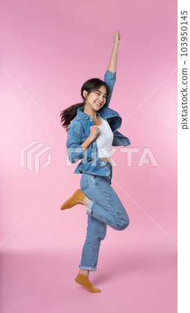 Young Asian woman wearing headphones dancing and listening to music from smartphone shoot in isolated on pink background Young Asian woman wearing headphones dancing and listening to music from smartphone shoot in isolated on pink background 103950145