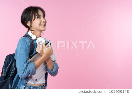 Portrait of smiling young Asian college student look to the side of the empty space with laptop and backpack isolated over pink background Portrait of smiling young Asian college student look to the side of the empty space with laptop and backpack isolated over pink background 103950148
