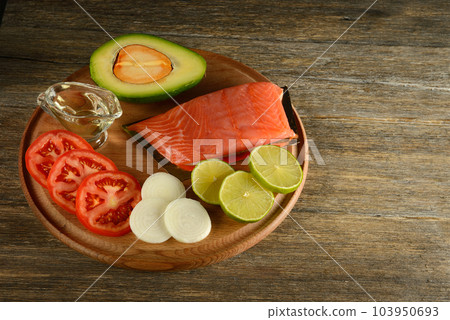 Meat red salmon fish, tomatoes, spices, onion, lemon and olive oil on kitchen table background. Copy space. Meat red salmon fish, tomatoes, spices, onion, lemon and olive oil on kitchen table background. Copy space. 103950693