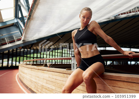 Young athletic woman in sportswear posing in studio against black