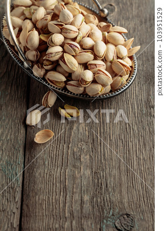 Salted pistachios on an old wooden table. 103951529