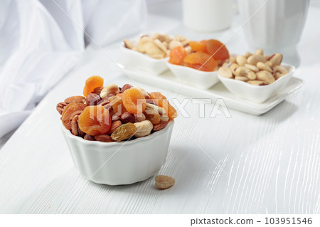 Dried fruits and assorted nuts on a white table. 103951546