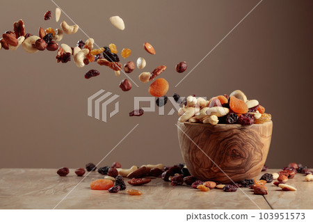 The mix of nuts and raisins in a wooden bowl. 103951573