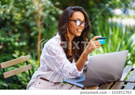 Young woman sitting at cafe making online shopping, using credit card and laptop. Online shopping. 103952765