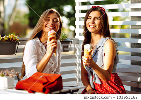 Two young female friends having fun and eating ice cream. Young women enjoy summer and vacation. 103953162
