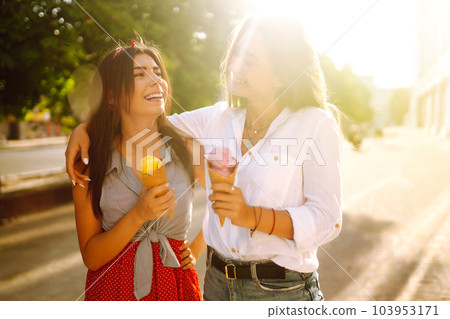 Two young female friends having fun and eating ice cream. Young women enjoy summer and vacation. 103953171