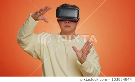Handsome man using virtual reality headset helmet to play simulation game app watching video content 103954944