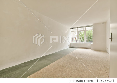 an empty room with white walls and green flooring on the right side, there is a window to the left 103956021
