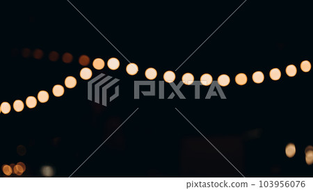 Decorative outdoor string lights at night time, Defocused Background, night city life backdrop, party time with Yellow bokeh balls 103956076