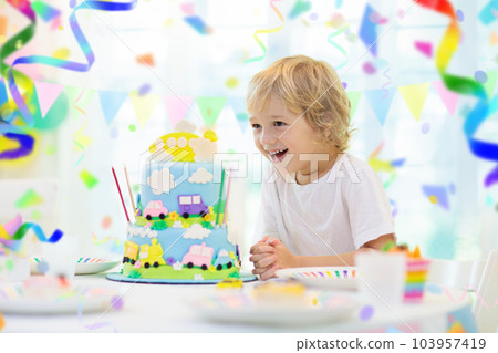 Kids birthday party. Child blowing out cake candle Kids birthday party. Child blowing out cake candle 103957419