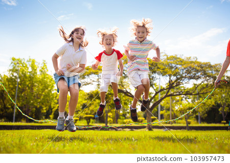 Happy kids play outdoor. Children skipping rope. Happy kids play outdoor. Children skipping rope. 103957473