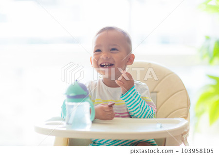 Baby eating solid foods in high chair. 103958105