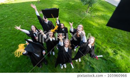 Classmates in graduation gowns throw their caps. View from above. Classmates in graduation gowns throw their caps. View from above. 103960966