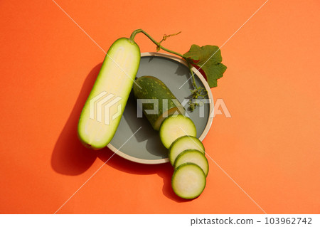 Over a colorful background, a round dish of winter melon slices is decorated on. Winter melon (Benincasa hispida) nutritional content makes it highly vital for human health Over a colorful background, a round dish of winter melon slices is decorated on. Winter melon (Benincasa hispida) nutritional content makes it highly vital for human health 103962742
