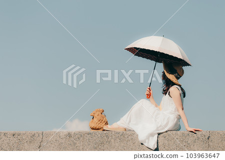 A woman standing on the embankment with a parasol 103963647