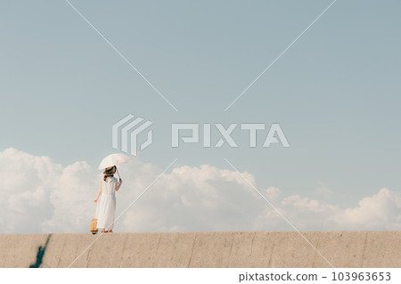 A woman standing on the embankment with a parasol A woman standing on the embankment with a parasol 103963653
