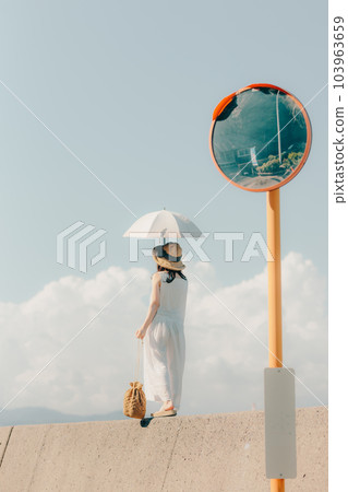 一位撐著遮陽傘站在堤岸上的女人 103963659