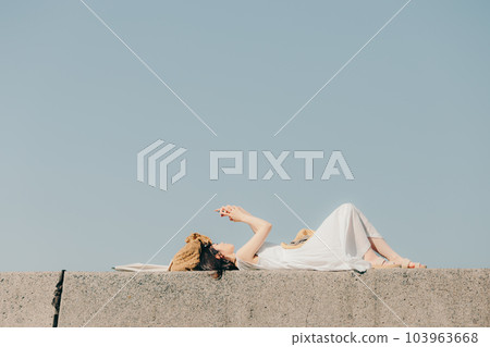 A woman lying on a hill and touching a smartphone A woman lying on a hill and touching a smartphone 103963668