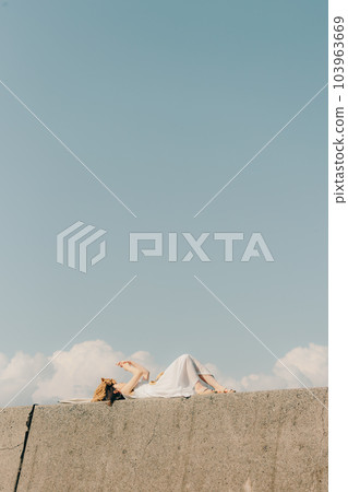 A woman lying on a hill and touching a smartphone A woman lying on a hill and touching a smartphone 103963669