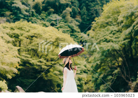 A woman standing by a mountain stream with a parasol 103965023
