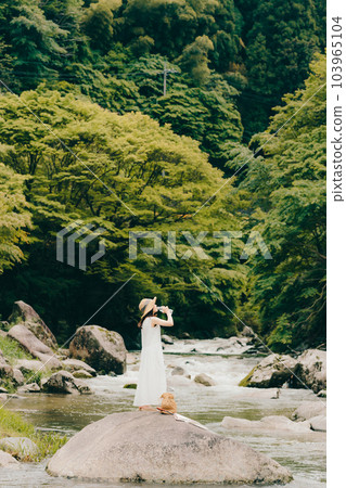 一個女人拿著塑料瓶站在山澗中 103965104