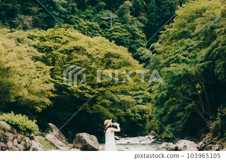 一個女人拿著塑料瓶站在山澗中 103965105