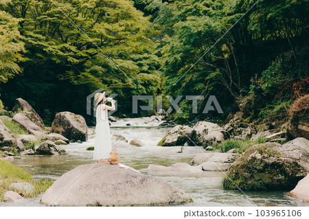 一個女人拿著塑料瓶站在山澗中 103965106