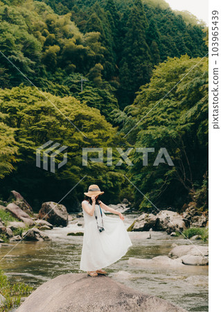A woman standing with a film camera in a mountain stream 103965439