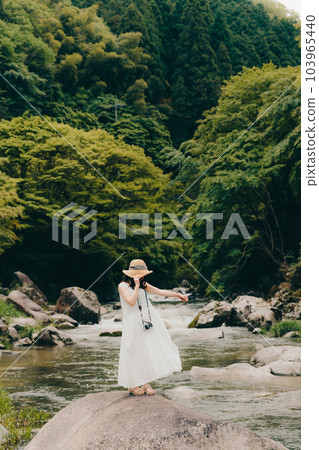 A woman standing with a film camera in a mountain stream 103965440