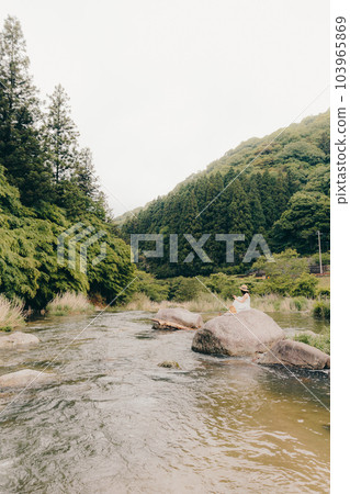 A woman holding a smartphone in a mountain stream 103965869