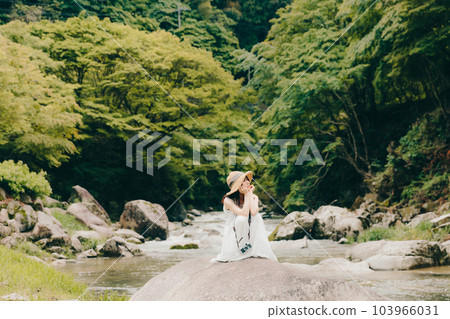 A woman holding a film camera in a mountain stream 103966031