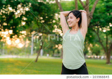 Female jogger. Fit young Asian woman with green sportswear stretching muscle in park before running and enjoying a healthy outdoor. Fitness runner girl in public park. Wellness being concept 103966645