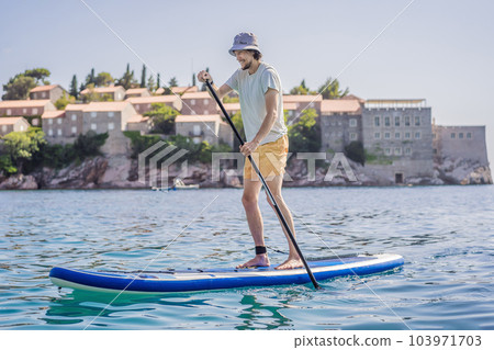 Young men Having Fun Stand Up Paddling in blue water sea near st stefan island in Montenegro. SUP 103971703