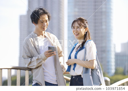 Young couple looking at smartphone together outdoors 103971854