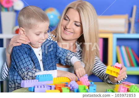 Woman and little boy playing with colorful plastic blocks together Woman and little boy playing with colorful plastic blocks together 103972853