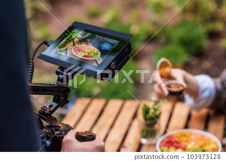 Photographer shooting a poke bowl on a professional camera in a park 103973128