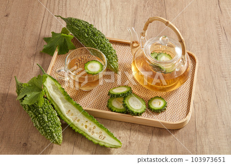 On the bamboo tray featured a transparent tea set with bitter melon. Bitter melon (Momordica charantia) tea has a lot of vitamin C and anti-aging substances On the bamboo tray featured a transparent tea set with bitter melon. Bitter melon (Momordica charantia) tea has a lot of vitamin C and anti-aging substances 103973651