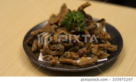 Crispy fried salmon skin served in a plate at the table. 103975297