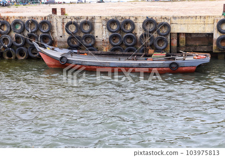 A small wooden fishing boat docking at the harbor. A small wooden fishing boat docking at the harbor. 103975813