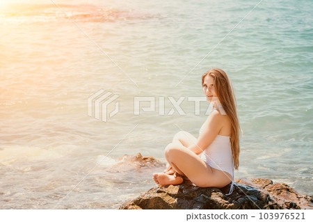 Woman summer travel sea. Happy tourist enjoy taking picture outdoors for memories. Woman traveler posing on the beach at sea surrounded by volcanic mountains, sharing travel adventure journey 103976521