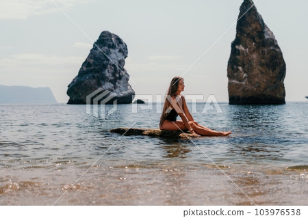 Woman summer travel sea. Happy tourist enjoy taking picture outdoors for memories. Woman traveler posing on the beach at sea surrounded by volcanic mountains, sharing travel adventure journey 103976538