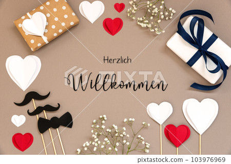 Flat Lay With Accessories, Gifts, Hearts, Text Herzlich Willkommen Means Welcome Flat Lay With Accessories, Gifts, Hearts, Text Herzlich Willkommen Means Welcome 103976969