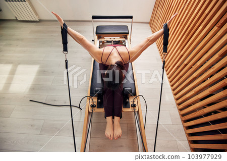 A young girl is doing Pilates on a reformer bed - Stock Photo