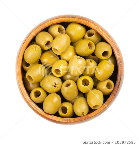 Pitted green olives for snacking, in a wooden bowl. Ready to eat, small table olives from Spain, processed after removing the kernel, preserved in brine. Used as a snack, as appetizer or as a garnish. 103978583